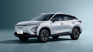En sølvfarvet kompakt elektrisk SUV i et studie, placeret til venstre, viser tydeligt dens front- og sideprofiler.