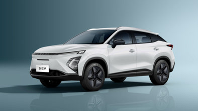 En hvid kompakt elektrisk SUV er parkeret på en lyseblå baggrund, set forfra fra venstre side.