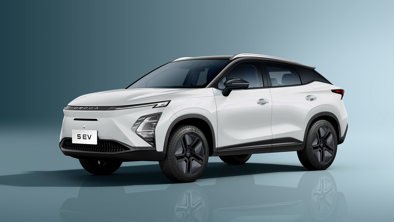 En hvid, moderne elektrisk SUV er parkeret i et studie med blågrå baggrund. Bilen har skarpe linjer og sorte detaljer.