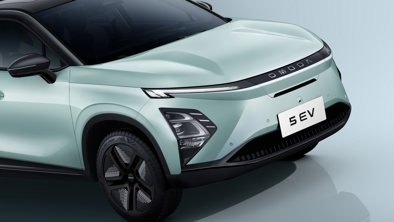 En lysegrøn OMODA 5 EV elbil set forfra til venstre med slanke forlygter og et glat, moderne design.