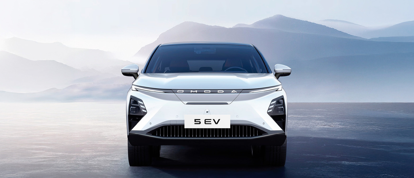 Frontbillede af en hvid Omoda 5 EV-bil parkeret på en glat overflade med bjerge synlige i baggrunden.